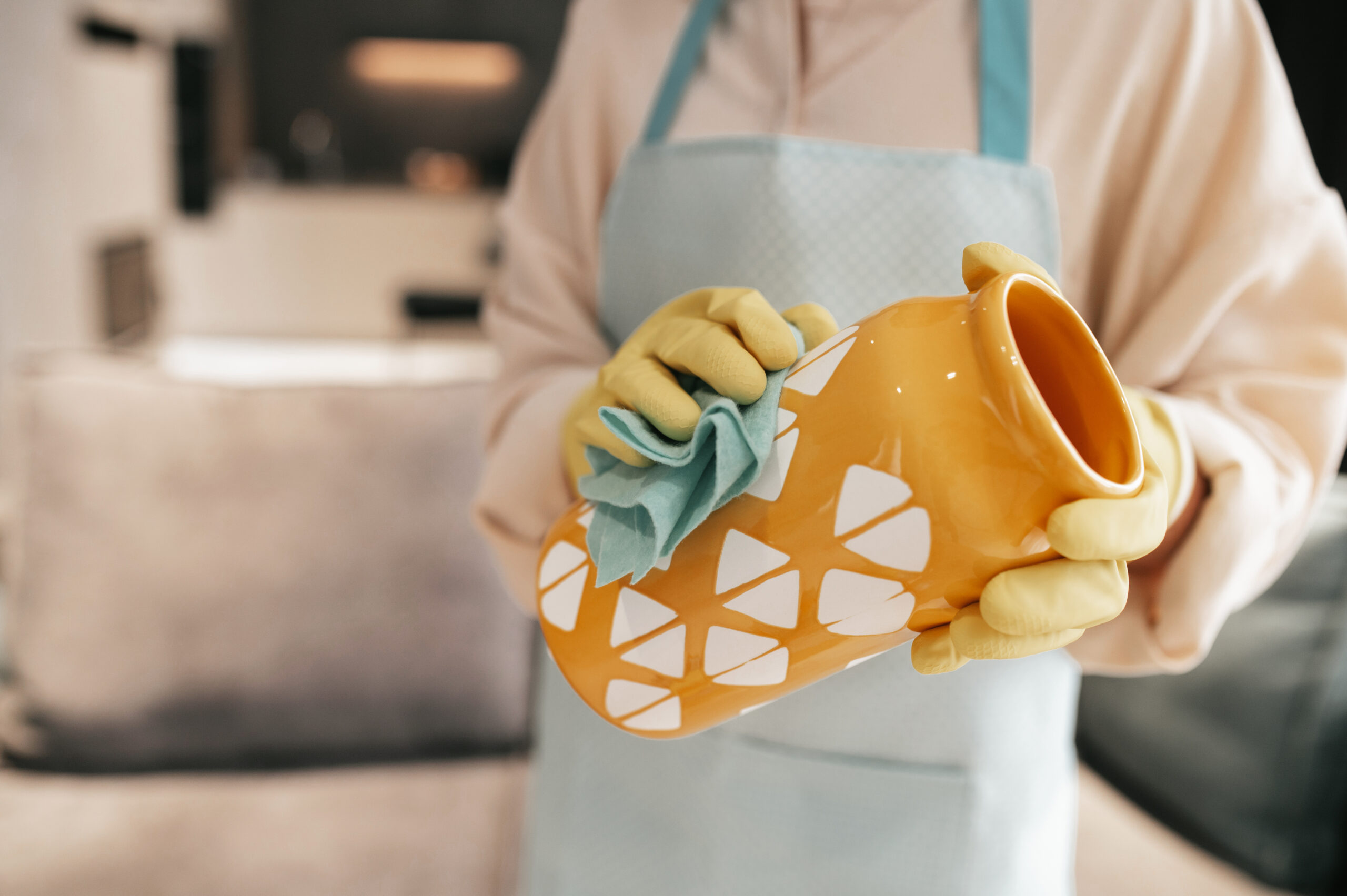 A woman in gloves cleaning an orange vase Cleaning crockery. A woman in gloves cleaning an orange vase